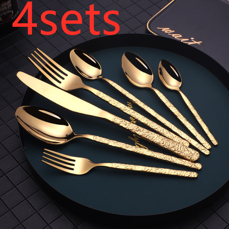 Shopi Vella gold cutlery set for dinner parties with ornate textured handles on black plate