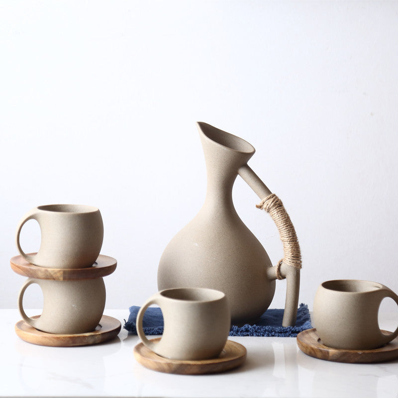 Handcrafted pottery pitcher set with four matching cups on wooden coasters for elegant drinkware