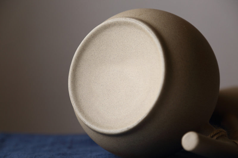Close-up view of handcrafted pottery pitcher set showing smooth textured base and spout