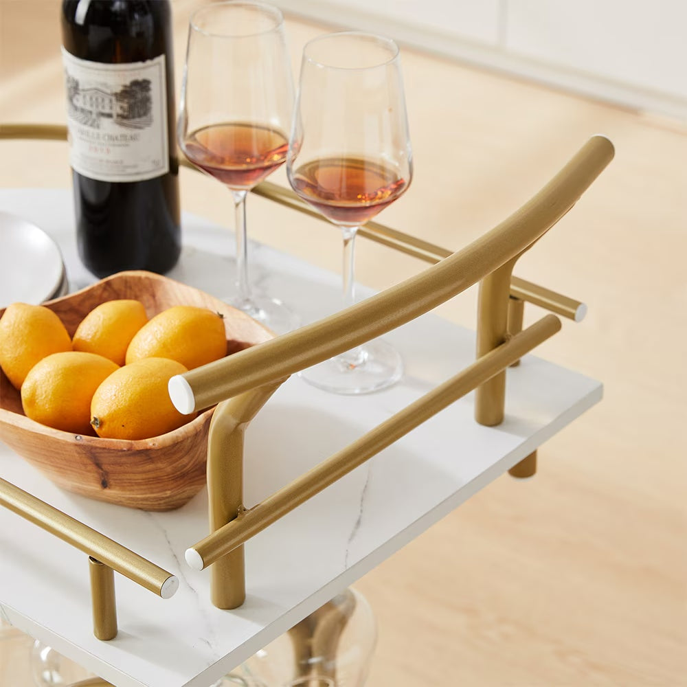 Modern bar trolley for home with white marble top, gold frame, and accessories including wine and lemons