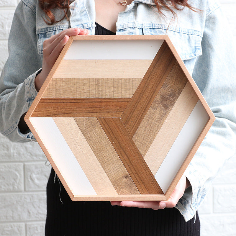 Person holding a hexagonal wooden modern dessert serving tray with mixed wood tones
