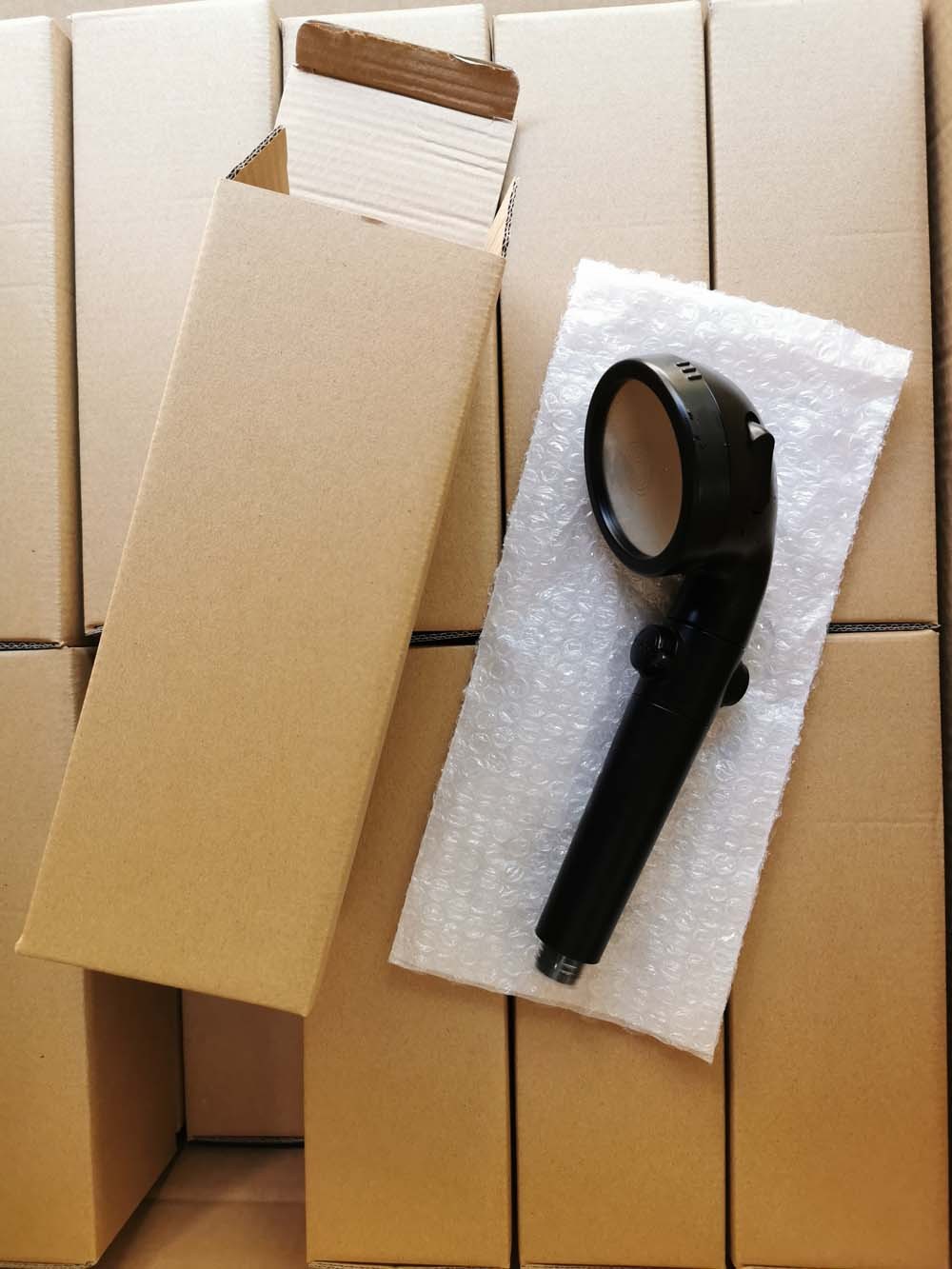 Shopi Vella negative ion shower head in black displayed on bubble wrap with open cardboard packaging