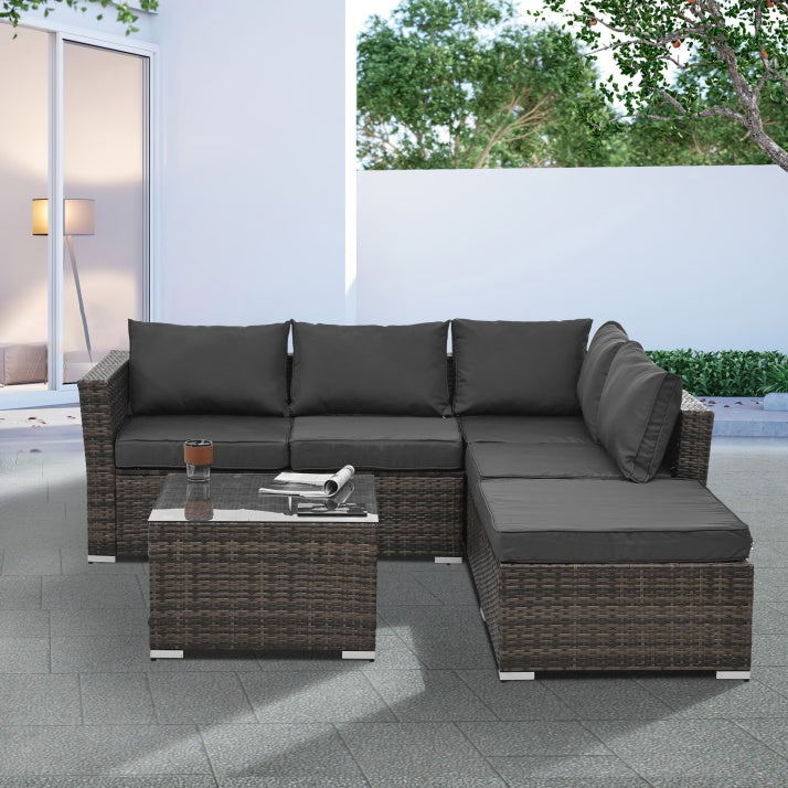Outdoor wicker patio furniture set with dark cushions and glass-top coffee table on patio