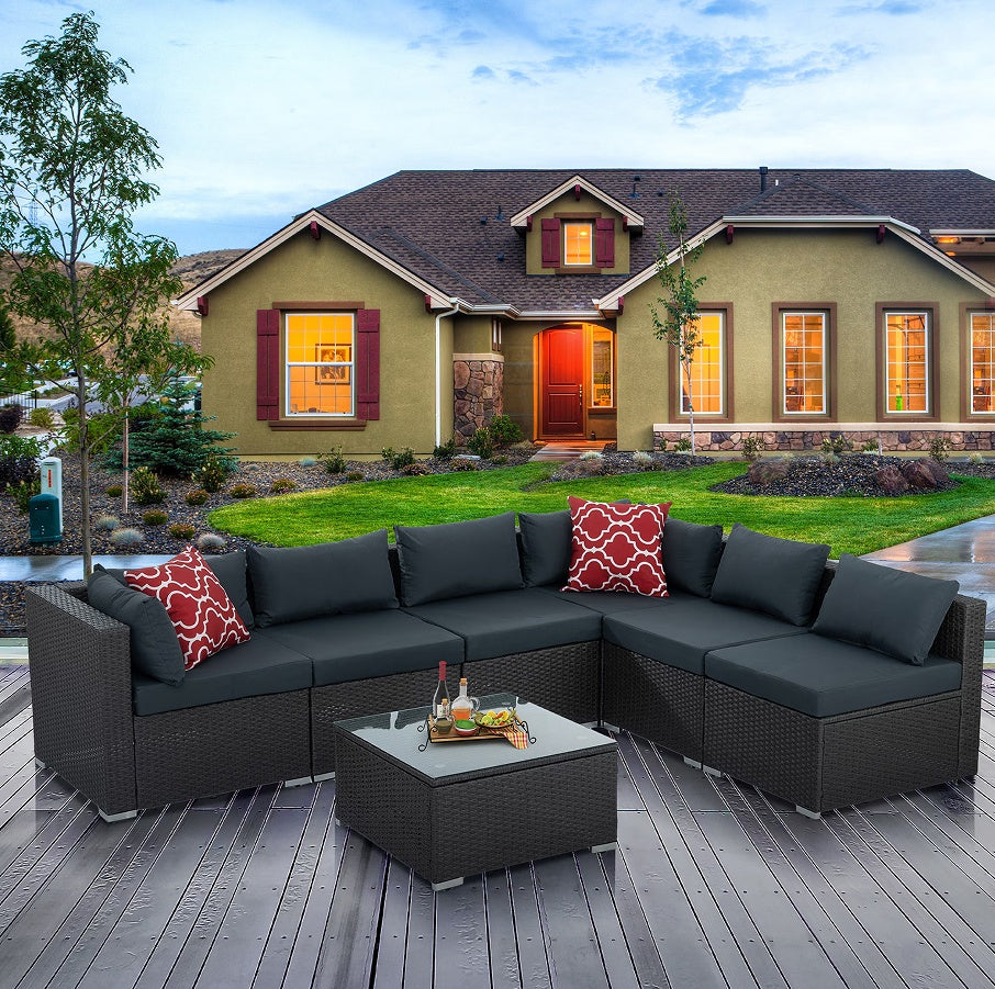 PE wicker patio furniture with coffee table and dark cushions set on wooden deck outside house