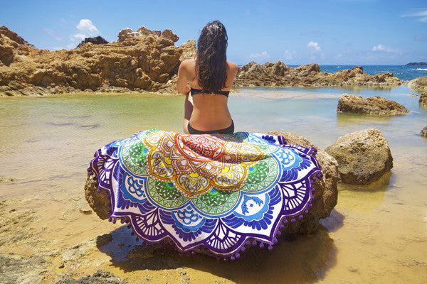 Woman sitting on rock near water with colorful polygon yoga mat round featuring intricate patterns