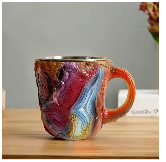 Colorful resin crystal coffee mug with textured surface and orange handle on wooden table