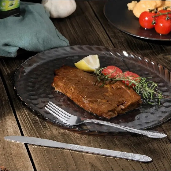 Shopi Vella stainless steel cutlery set with knife and fork beside steak on rustic plate