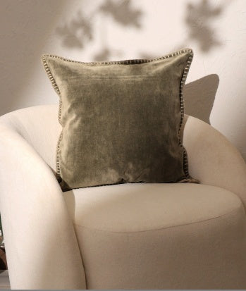 Shopi Vella stonewashed velvet throw pillow case in muted olive green on cream chair