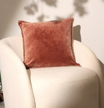 Shopi Vella stonewashed velvet throw pillow case in warm rust color on white modern chair