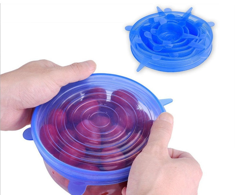 Blue stretch silicone food covers sealing bowl of grapes held by hands for kitchen storage