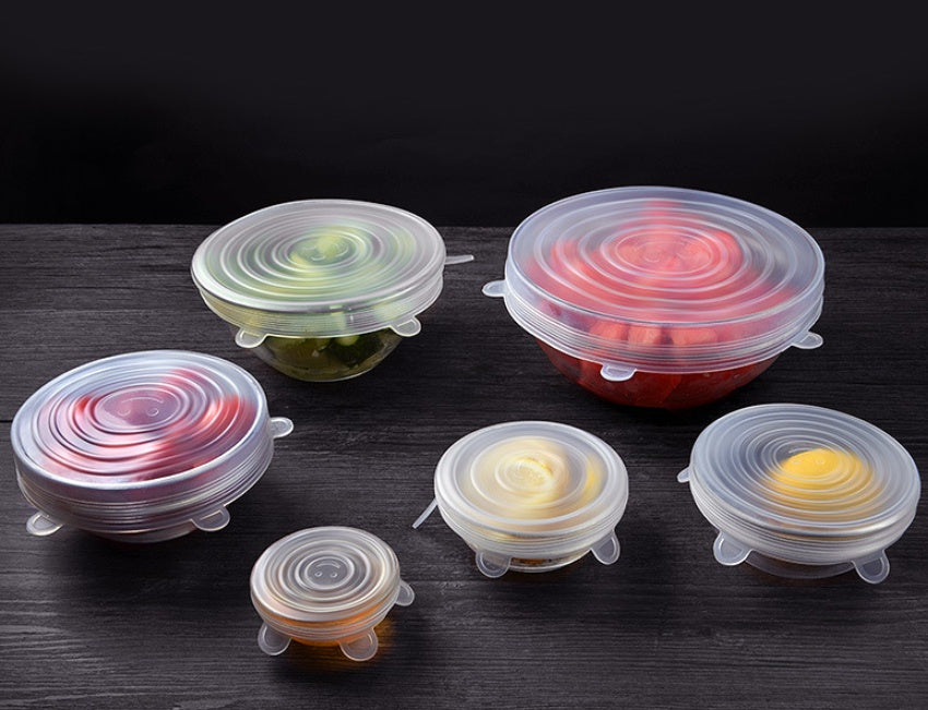 Set of stretch silicone food covers in various sizes sealing bowls with fresh fruits and vegetables
