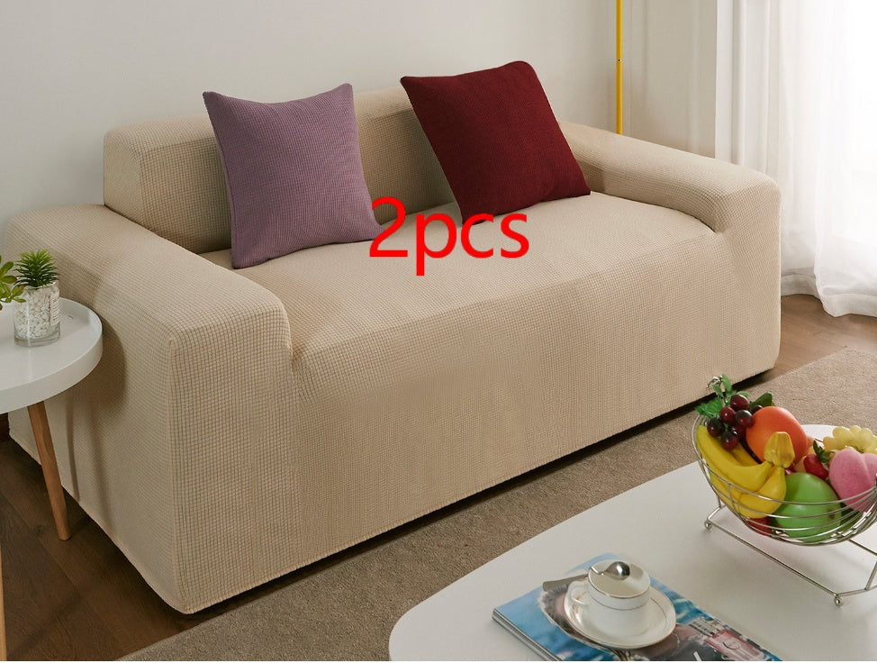 Beige waterproof sofa slipcover on a modern couch with two decorative pillows in a living room
