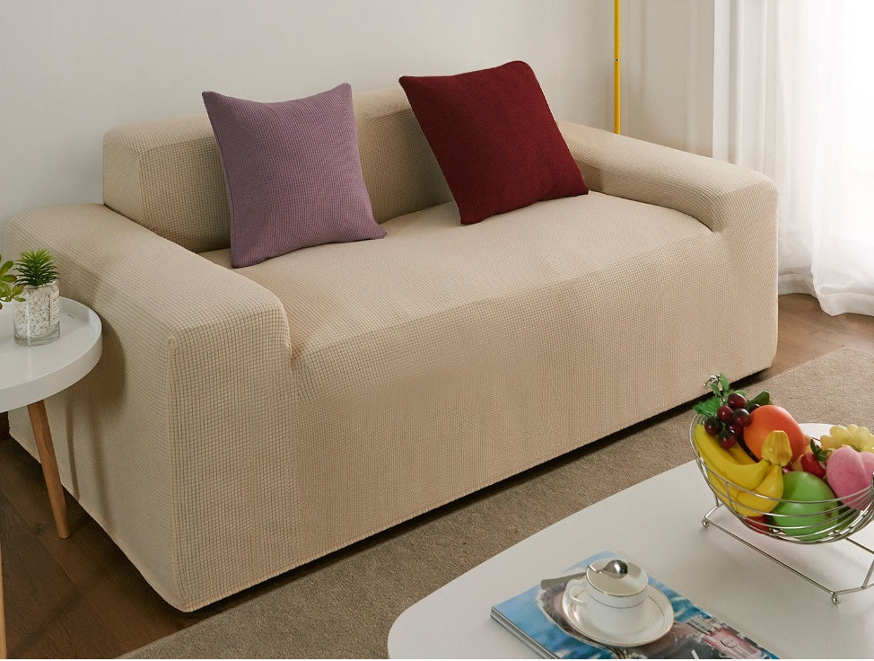 Beige waterproof sofa slipcover on modern sofa with purple and red pillows in living room