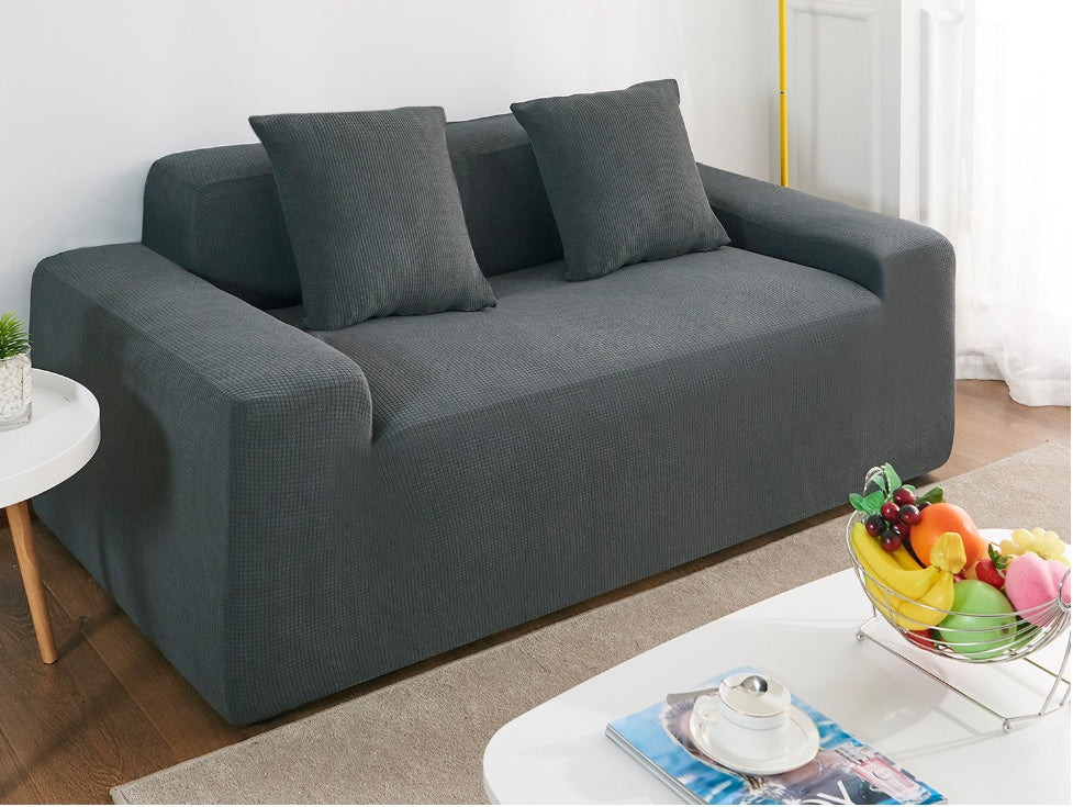 Shopi Vella waterproof sofa slipcover in dark gray on a modern sofa with matching cushions in a bright living room