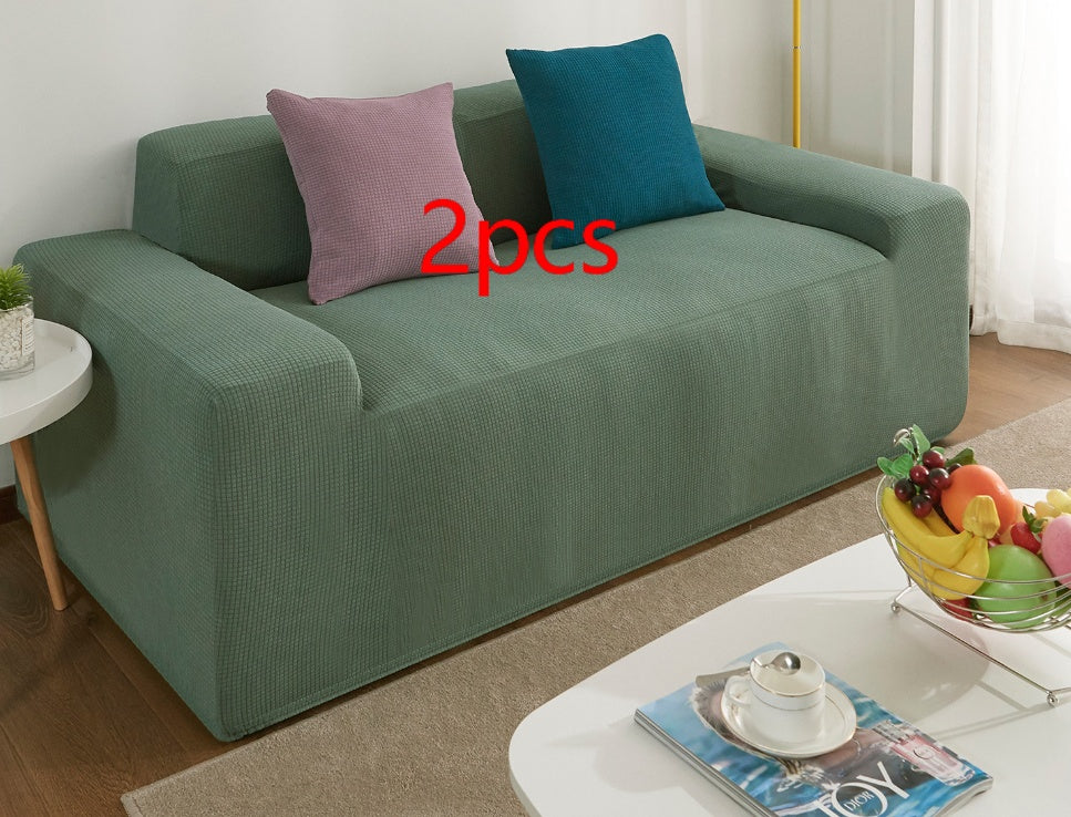 Shopi Vella waterproof sofa slipcover in green fitted on a two-seat sofa with decorative pillows