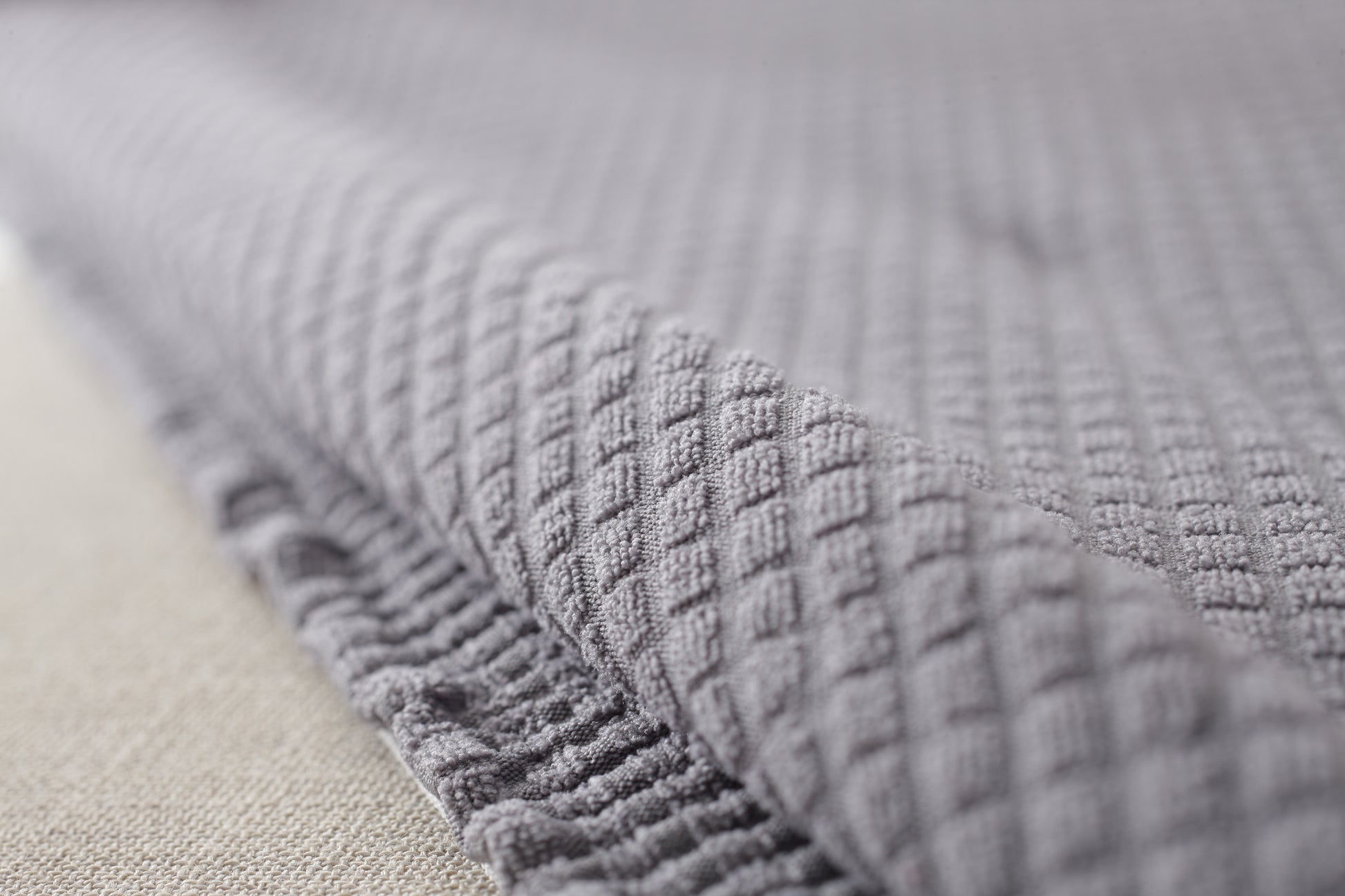 Close-up of gray textured waterproof sofa slipcover fabric by Shopi Vella for home storage protection