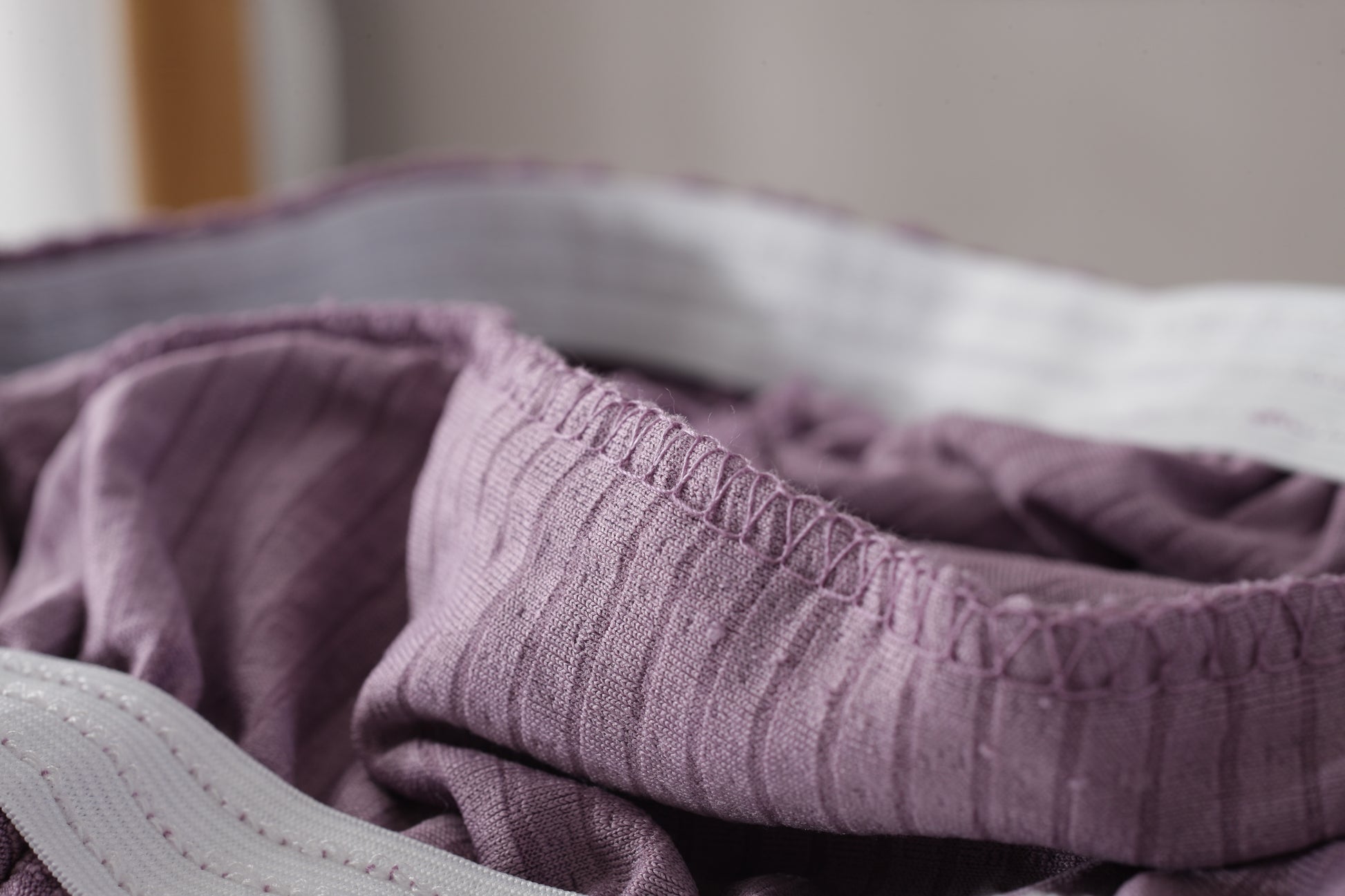 Close-up of Shopi Vella waterproof sofa slipcover fabric in textured purple material for home storage