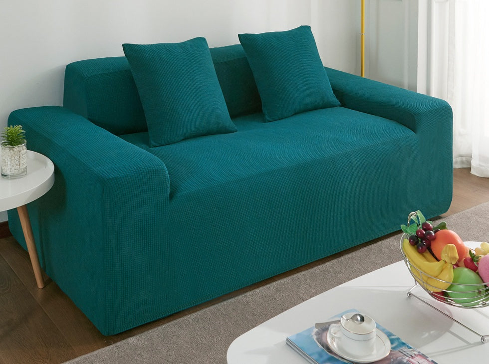 Teal waterproof sofa slipcover by Shopi Vella on a modern sofa with matching cushions in a living room