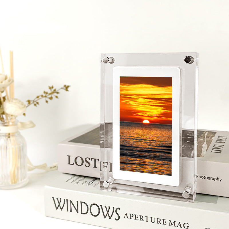 Shopi Vella vertical digital photo frame with battery displaying sunset over ocean on a stack of books