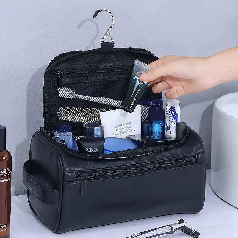 Black vintage waterproof makeup bag hanging with multiple skincare products inside and hand reaching for a tube