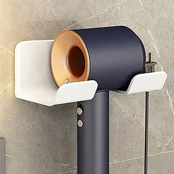 Wall mounted bathroom hair dryer rack holding a modern black and gold hair dryer on gray tile wall