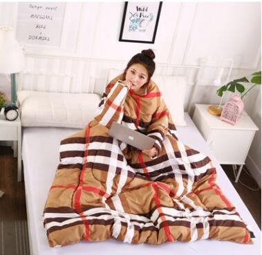 Shopi Vella winter quilt with sleeves in brown, white, and red plaid design wrapped around woman on bed
