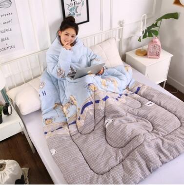Shopi Vella winter quilt with sleeves in blue and gray with bear design, worn by woman sitting on bed