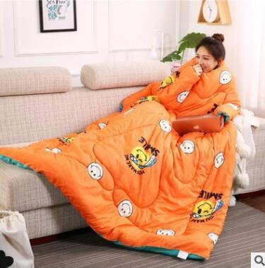Shopi Vella orange winter quilt with sleeves featuring smiley face designs worn by woman on couch