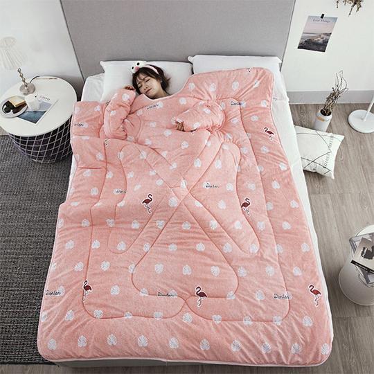 Shopi Vella pink winter quilt with sleeves featuring flamingo and leaf patterns on bed