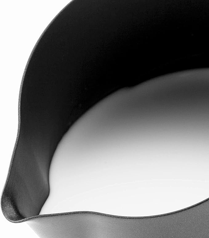 Close-up of black stainless steel milk frothing pitcher with smooth curved spout for precise pouring