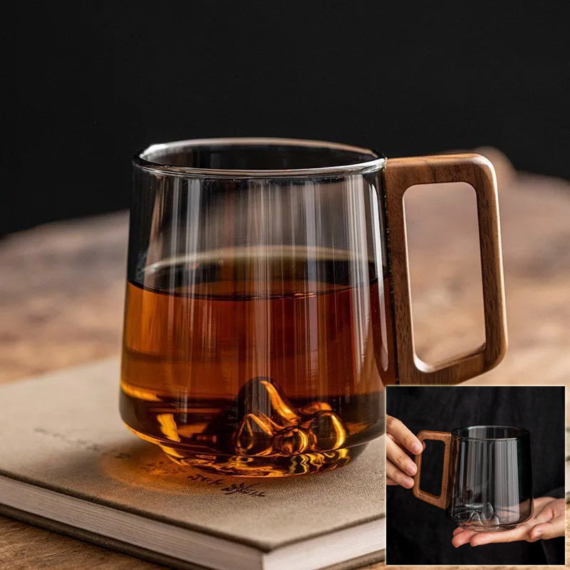 Shopi Vella wooden handle glass cup filled with amber liquid placed on a closed book